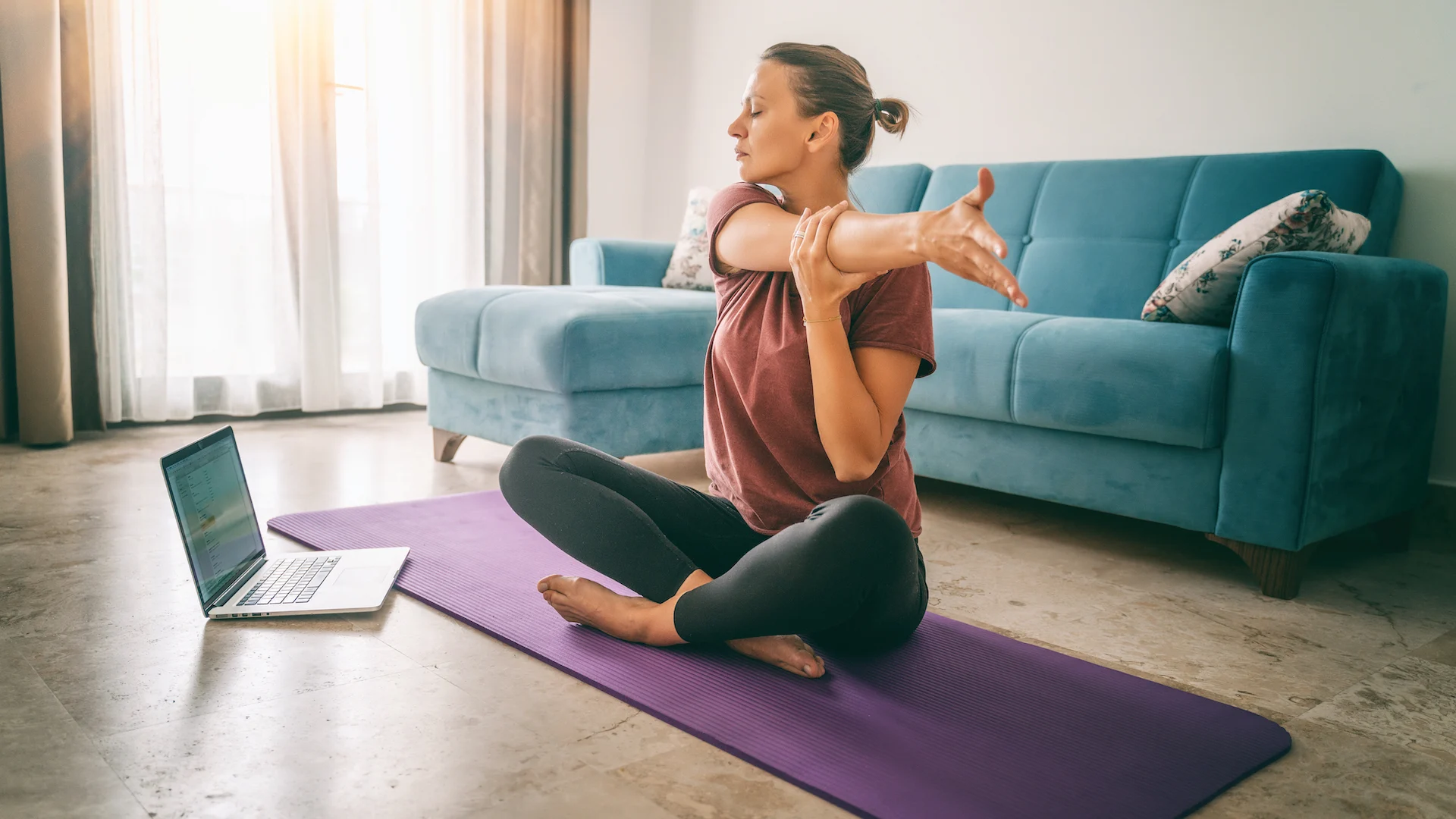 Woman stretching on a yoga mat at home